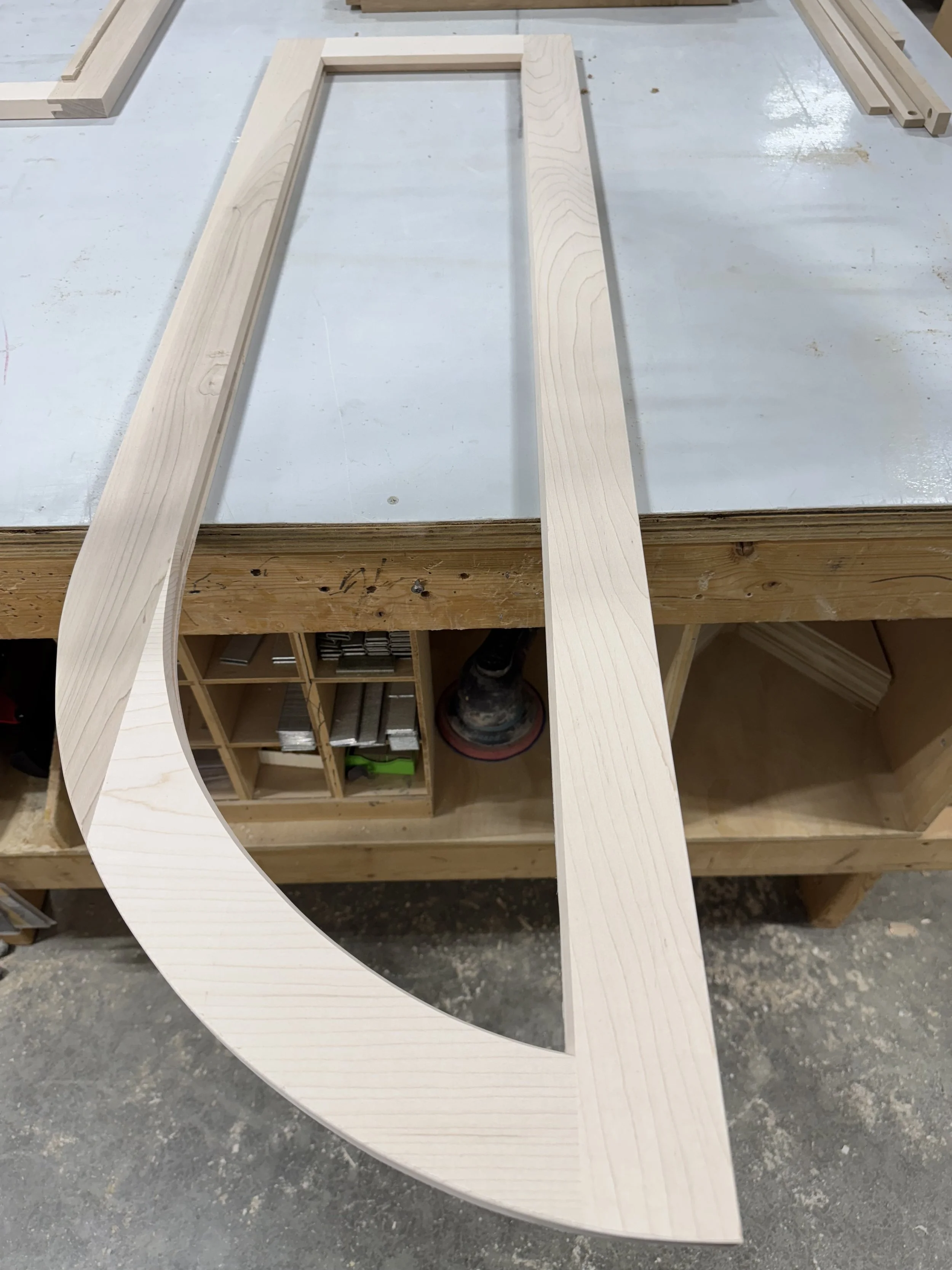 Wooden frame with a curved cutout on the bottom left side, placed on a workshop workbench.