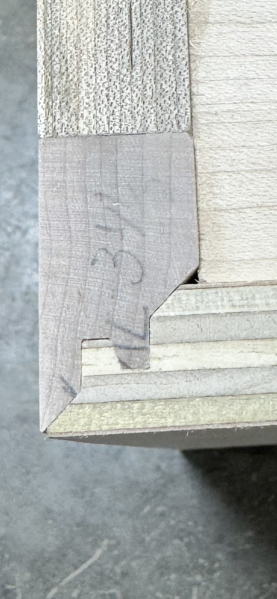 Close-up of the corner of a wooden structure showing weathered wood planks and trim details.