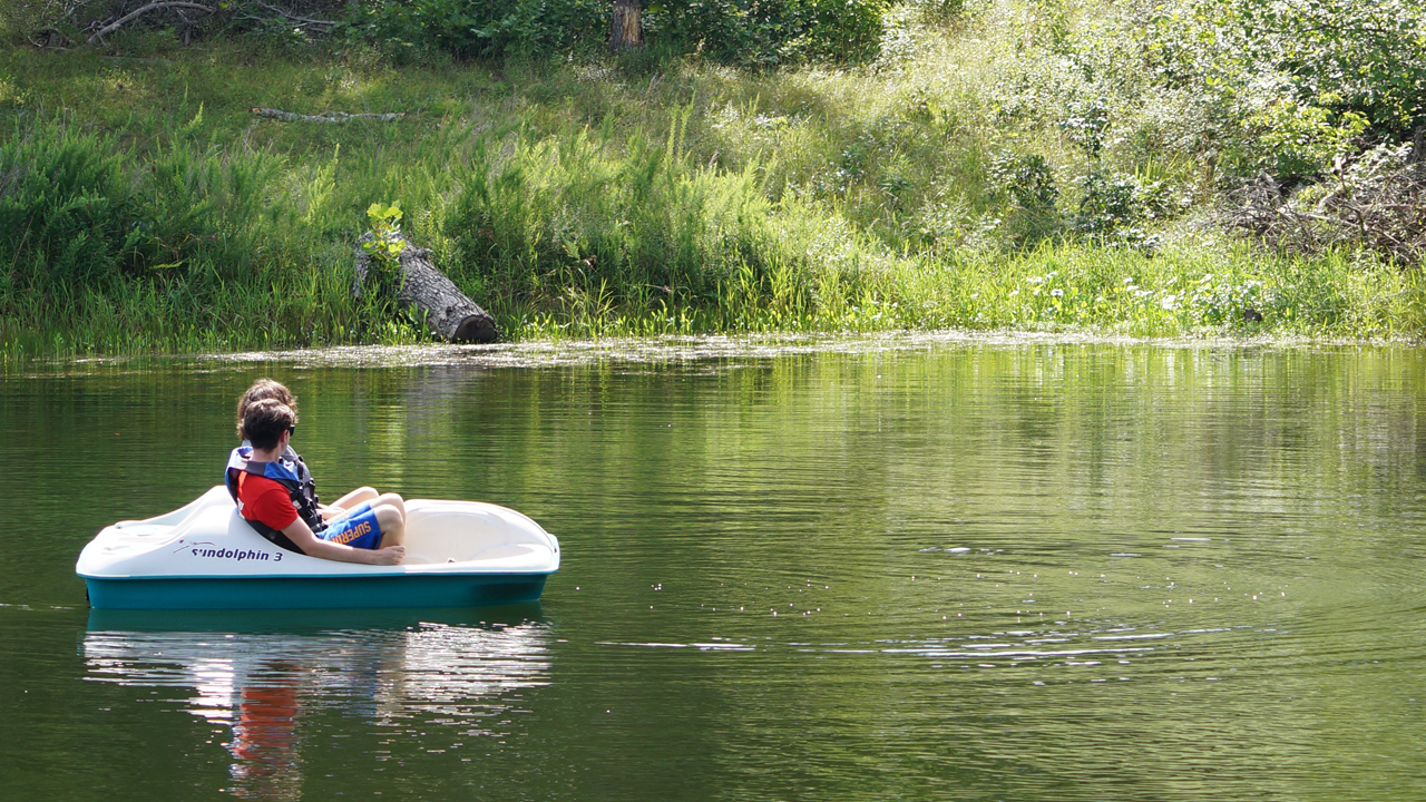 Two People Sitting in White Paddle Boat on a Lake