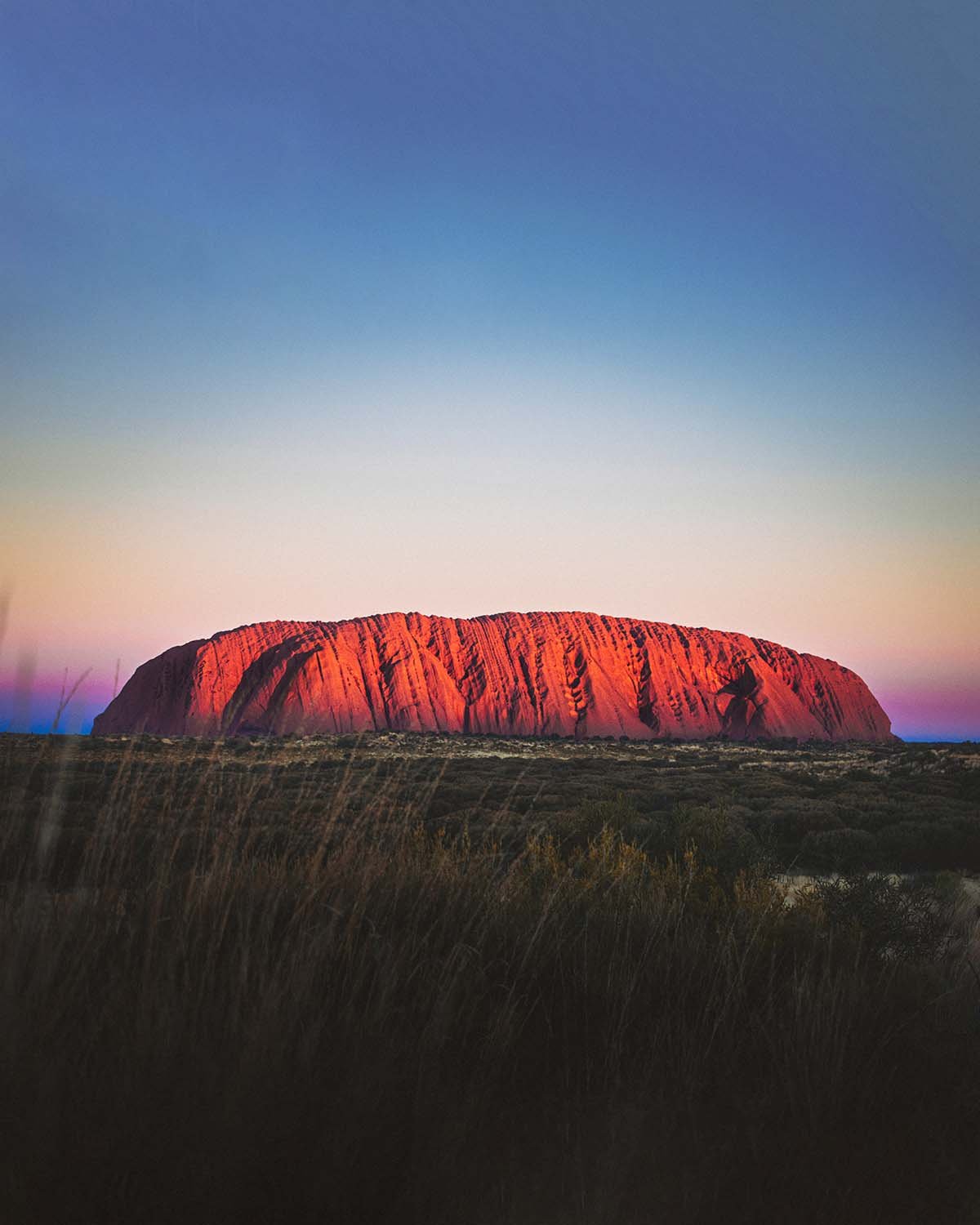 Le géant spirituel. Uluru s'embrase d'un rouge intense quelques minutes avant la nuit.