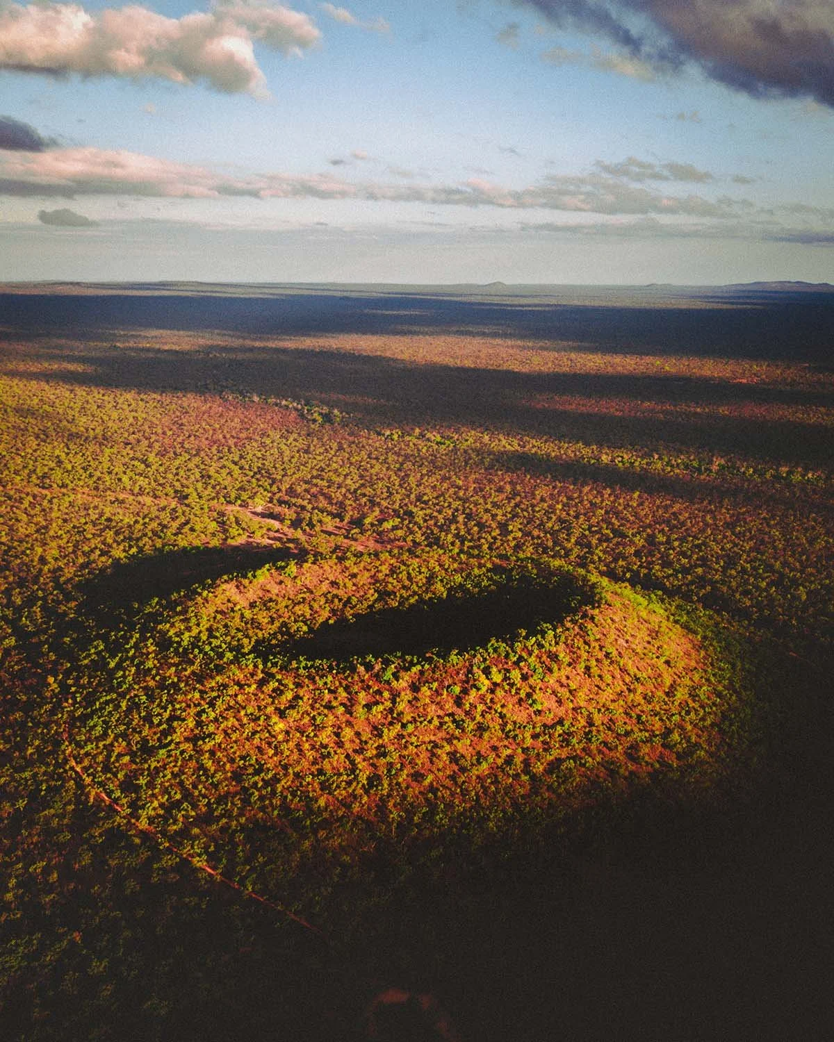 Lumière rasante sur un cratère ancien. La texture du bush australien se révèle sous le soleil couchant."