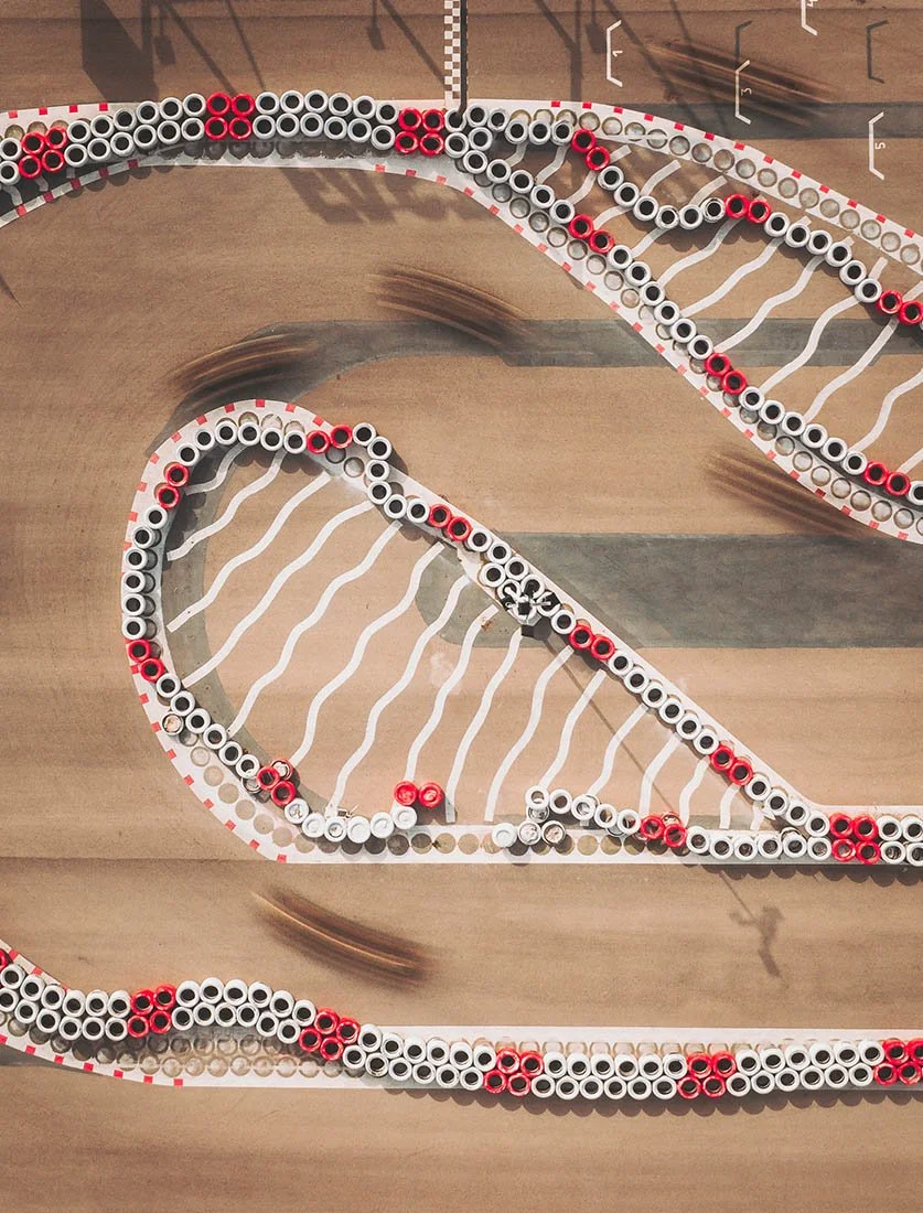 Vue aérienne top-down graphique d'un circuit de karting, mettant en valeur les courbes, les vibreurs et la trajectoire.