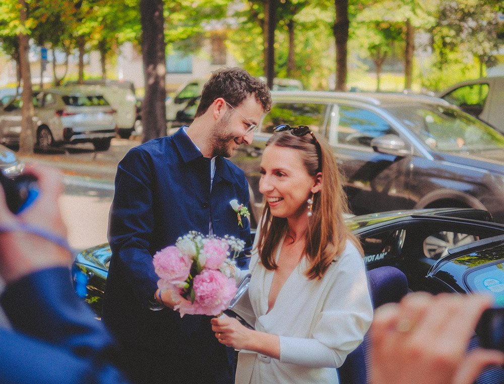 Instant de joie spontané : les mariés près de leur voiture de collection décapotable après la cérémonie civile. Reportage de mariage naturel et élégant à Paris/IDF.