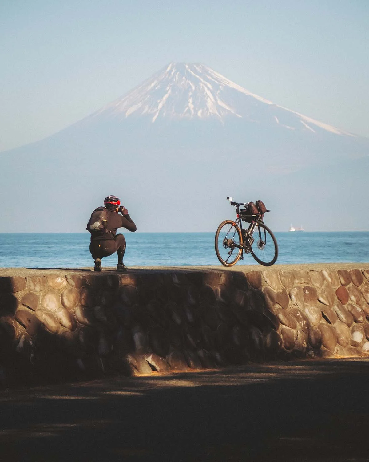Cycliste posant son vélo pour photographier le Mont Fuji depuis la côte de Shizuoka (probablement près de Numazu ou Miho no Matsubara). Tourisme à vélo au Japon.