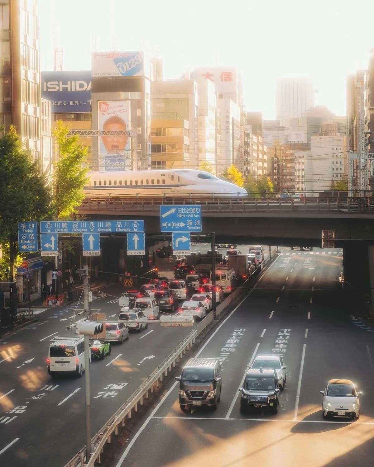 Train grande vitesse Shinkansen N700 passant sur pont au-dessus traffic routier dense voitures Tokyo quartier Shinagawa coucher soleil. Photo urbaine infrastructure transport ferroviaire voyage Japon modernité.
