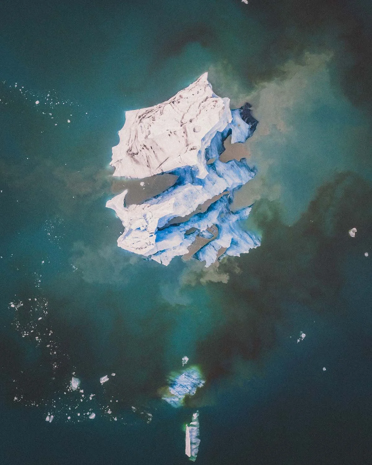 Détail graphique vu du ciel des icebergs flottant dans le lagon glaciaire de Jökulsárlón. Nuances de bleu et de blanc capturées par Dimitri Weber.