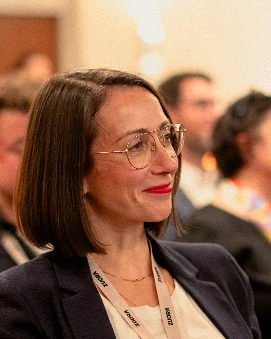 Participante attentive et souriante dans le public d'une conférence. Une image corporate qui illustre l'engagement et l'intérêt des collaborateurs lors de vos séminaires.