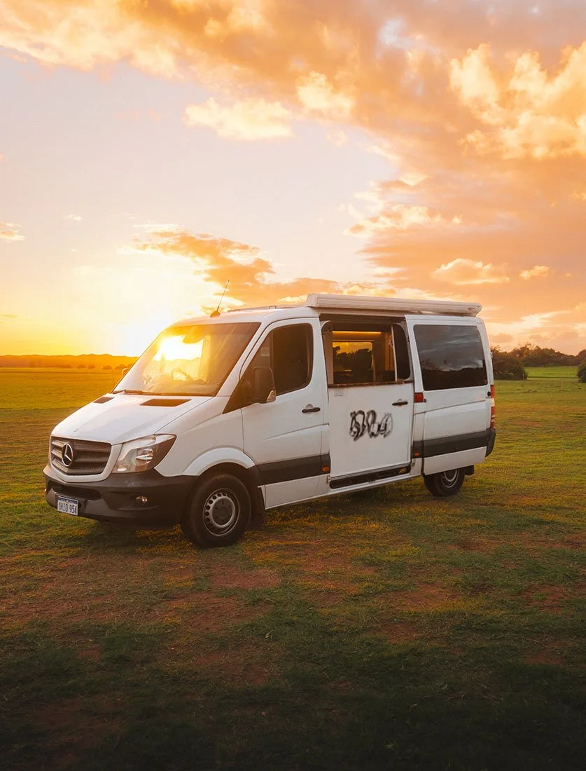Ambiance Vanlife : Mercedes Sprinter aménagé stationné dans un champ au coucher du soleil. Photographie lifestyle, voyage et liberté.