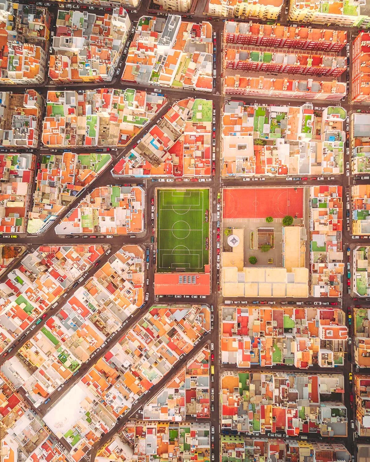 Vue graphique (top-down) de l'urbanisme dense et coloré de Las Palmas de Gran Canaria, avec un terrain de sport au cœur du quartier résidentiel.