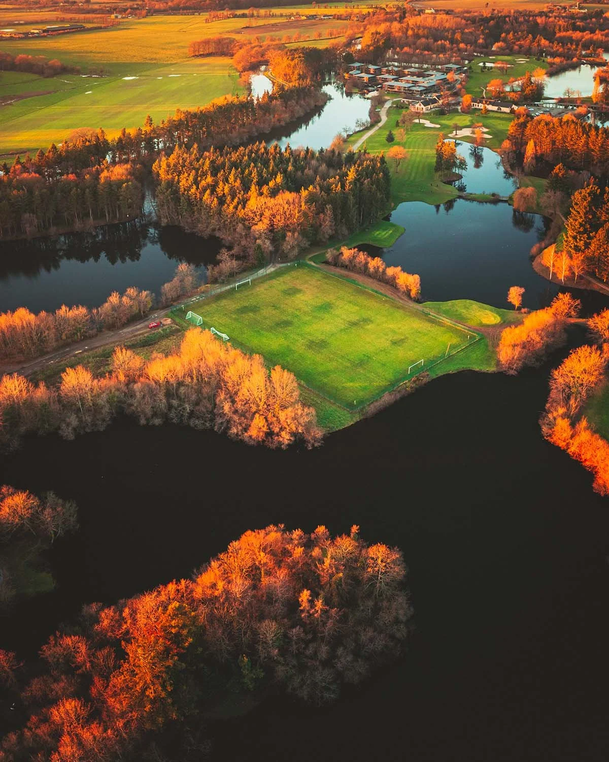 Lumière d'automne. Ombres longues et couleurs chaudes sur un parcours de golf arboré en fin de journée.