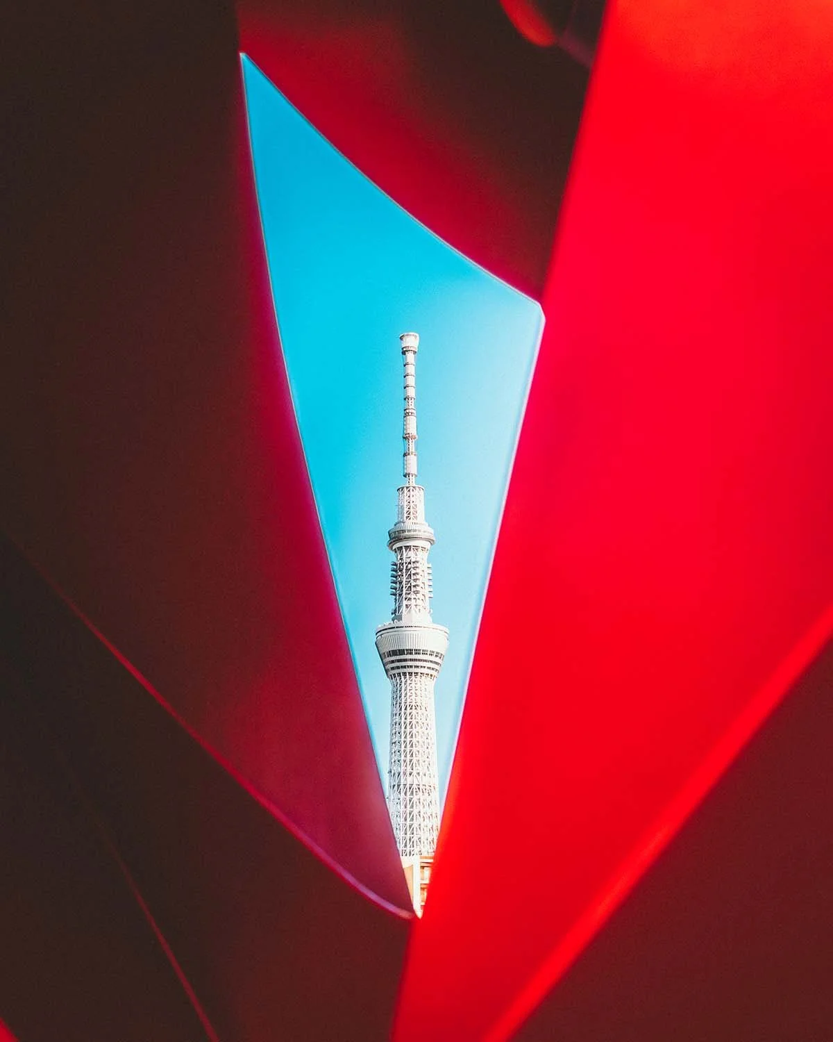 Composition architecturale abstraite utilisant une structure rouge pour encadrer géométriquement la tour Tokyo Skytree sur fond de ciel bleu. Art par Dimitri Weber.