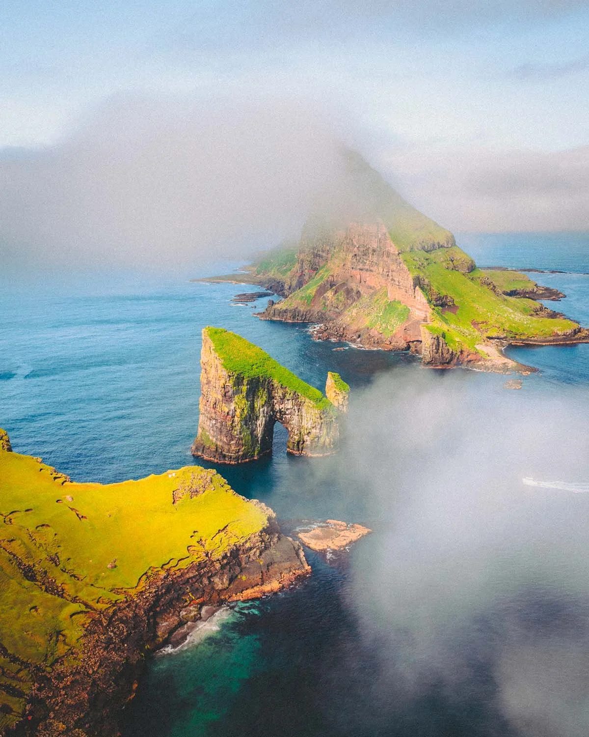 Vue aérienne époustouflante des aiguilles rocheuses de Drangarnir et de la célèbre arche naturelle dans la mer, au large de l'île de Vágar.