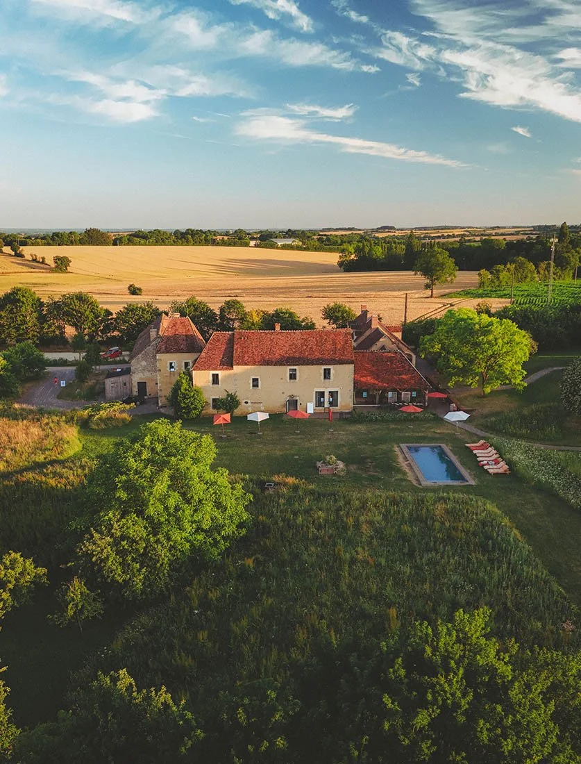 Vue aérienne spectaculaire d'un lieu de réception de mariage à la campagne (Domaine/Mas) avec piscine, baigné par la lumière dorée. Mise en valeur des lieux d'exception.
