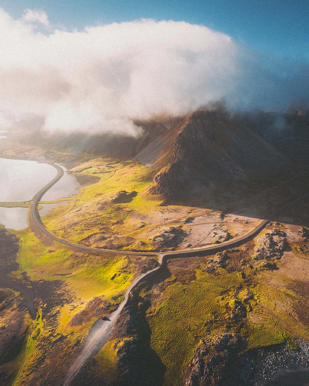 Le phare orange vif de Hvalnes (Austurland) se détachant sur un fond de montagnes sombres et de nuages dramatiques. Paysage côtier islandais.