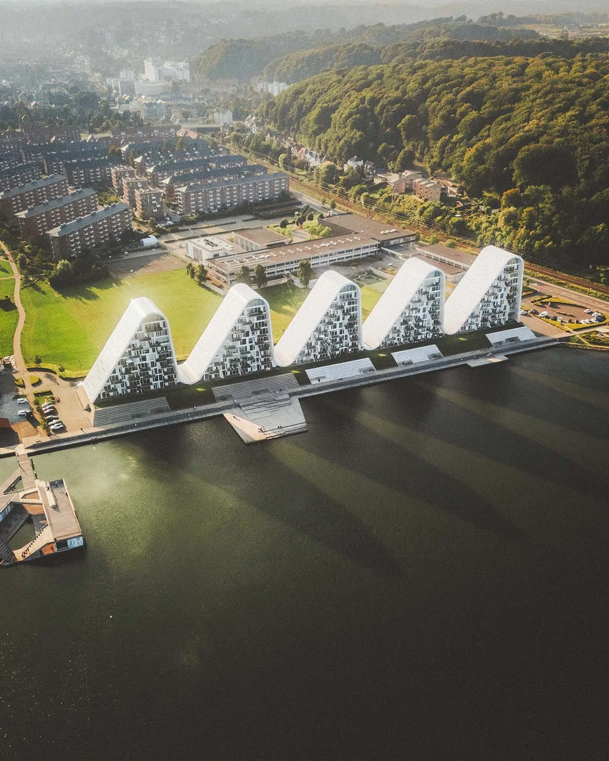 Architecture iconique scandinave : le complexe résidentiel "The Wave" à Vejle au Danemark, se reflétant dans le fjord. Photo d'architecture par Dimitri Weber.
