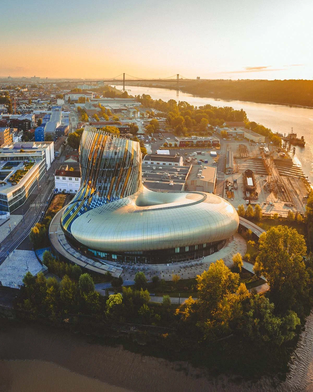 Tourbillon d'or. La Cité du Vin reflète le soleil couchant sur la Garonne, hommage moderne à l'âme de la région.