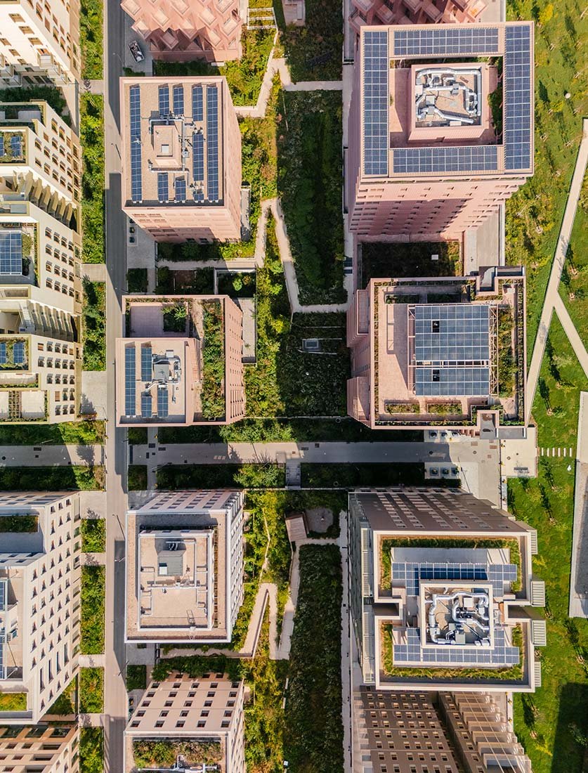 Vue aérienne verticale (Top-down) d'un complexe résidentiel moderne équipé de toitures végétalisées et panneaux solaires. Une image graphique pour valoriser l'architecture durable, signée Dimitri Weber, télépilote drone certifié à Paris.