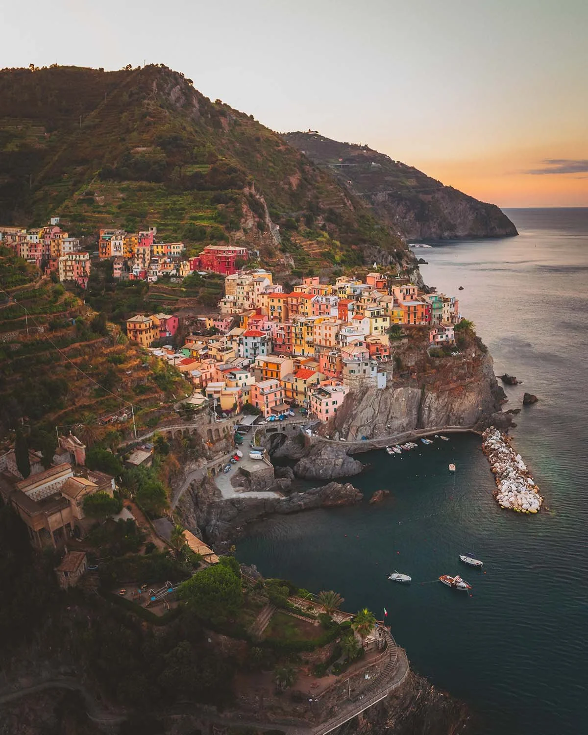 Le village accroché. Manarola s'illumine au crépuscule, maisons pastel défiant la gravité au-dessus de la mer Ligure.