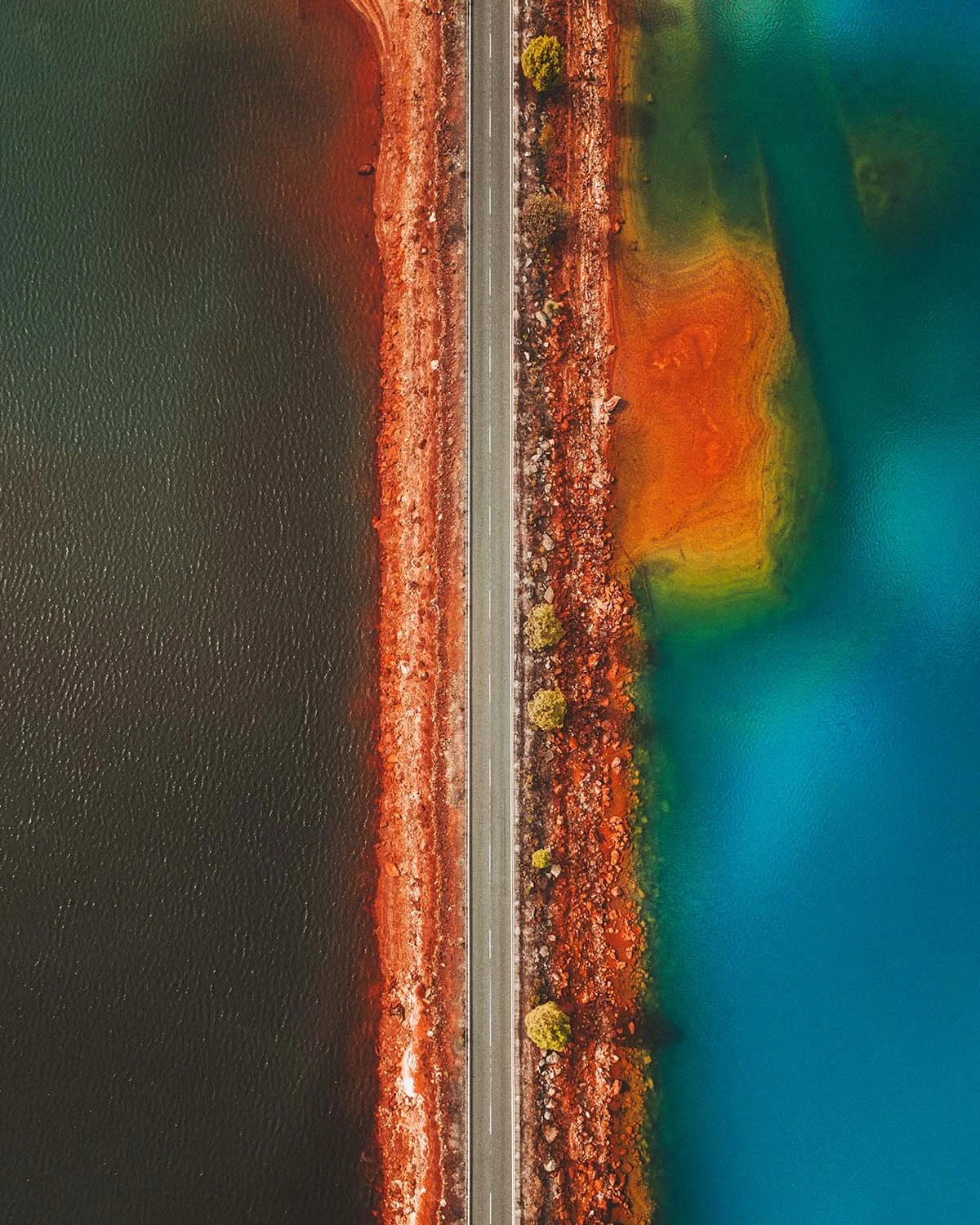 Frontière chimique. Une route solitaire tranche le paysage, séparant le bleu profond des eaux minérales oxydées.