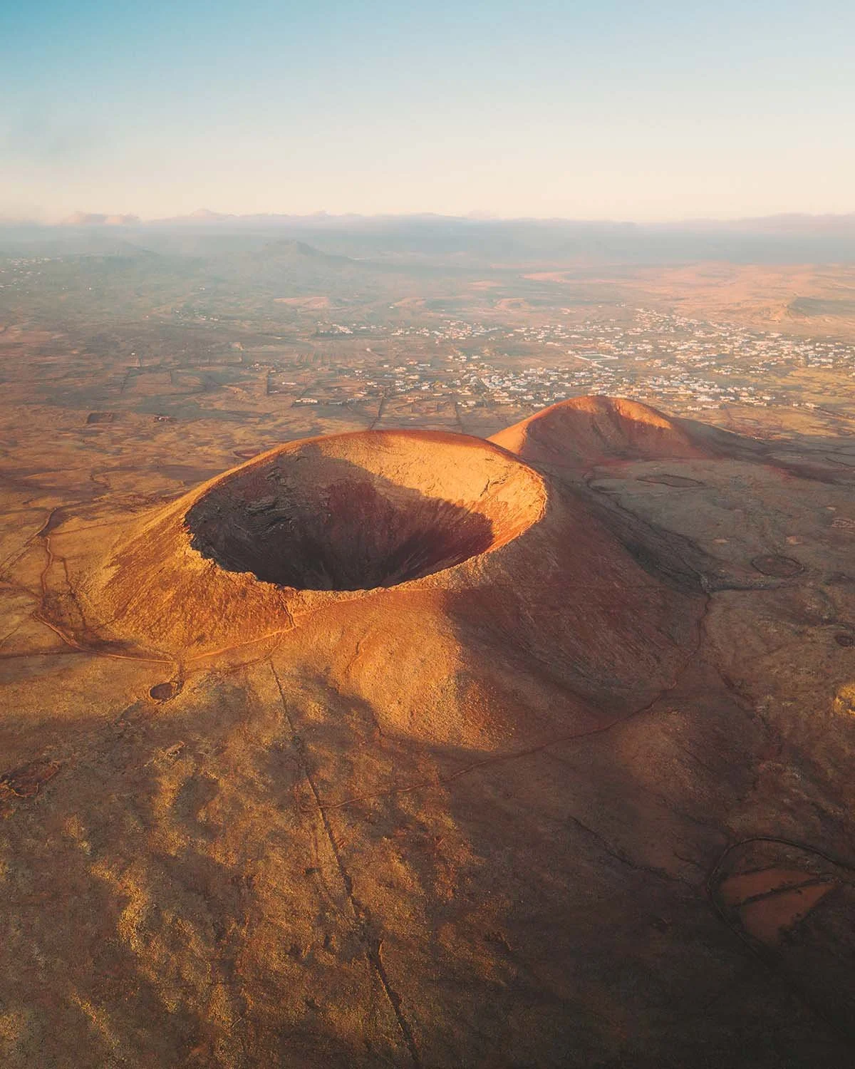 Gros plan aérien sur la caldeira ouverte d'un volcan près de Lajares à Fuerteventura, baigné par la lumière chaude du lever de soleil.