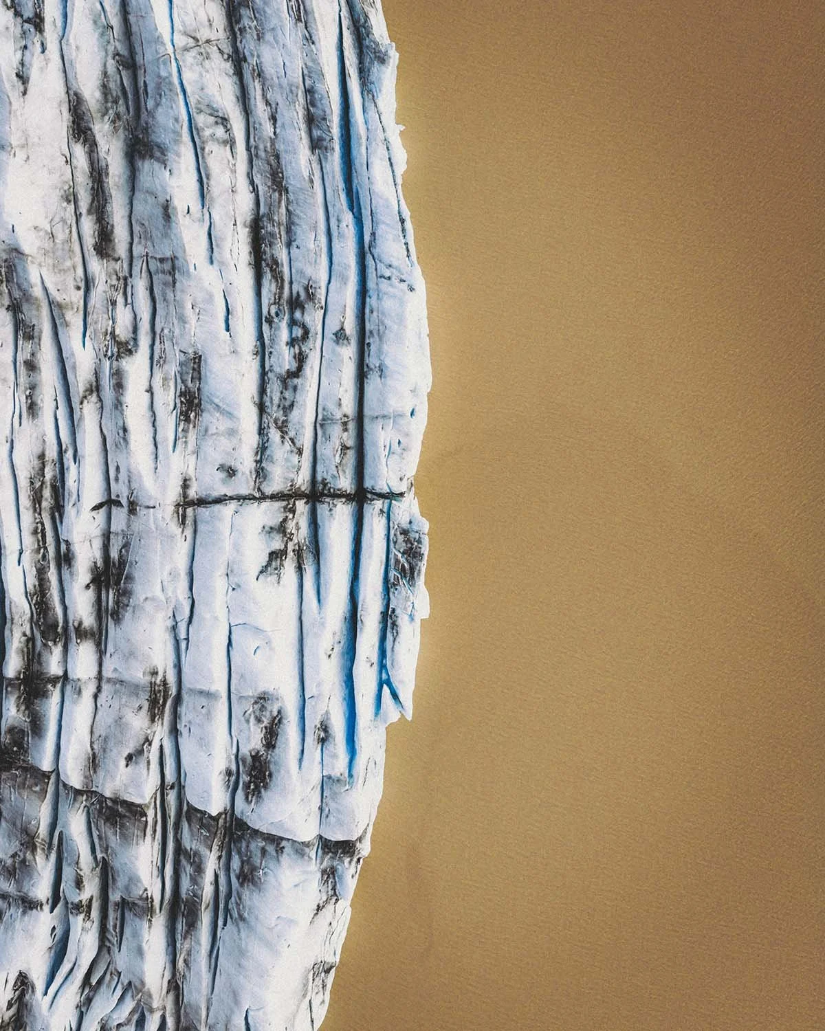 Vue zénithale abstraite des crevasses bleues et de la glace noire d'un glacier (type Sólheimajökull ou Skaftafell) sur la côte sud de l'Islande.