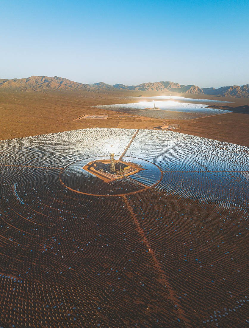 Photographie industrielle par drone : immensité d'une centrale solaire thermodynamique et ses miroirs au coucher du soleil.