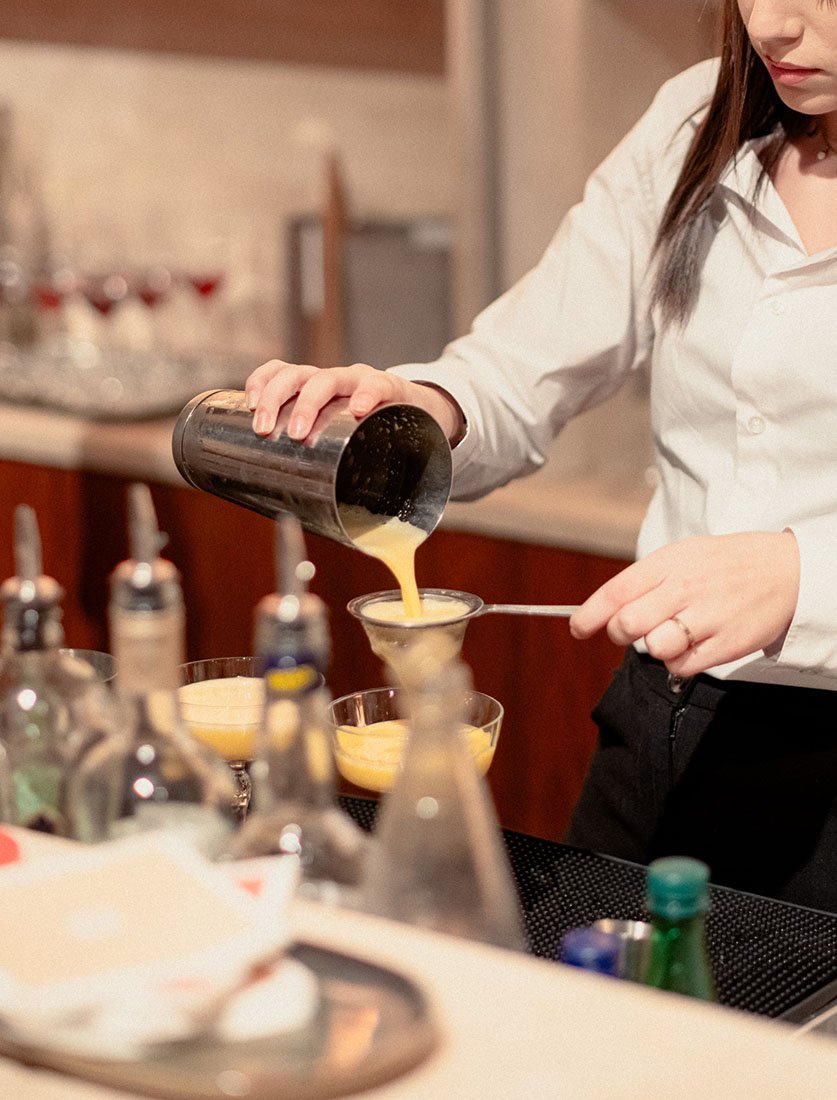 Gros plan sur la préparation d'un cocktail (mixologie) au shaker. Image dynamique pour bars, hôtels et cartes de boissons.