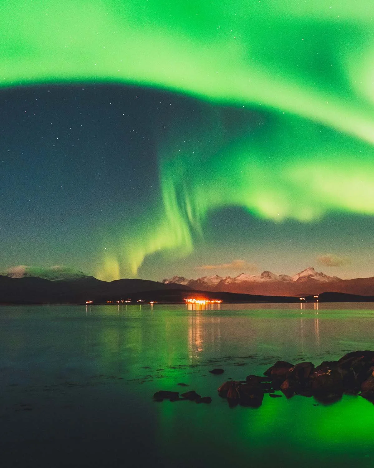 Explosion solaire. Une arche lumineuse traverse le ciel polaire au-dessus des fjords.