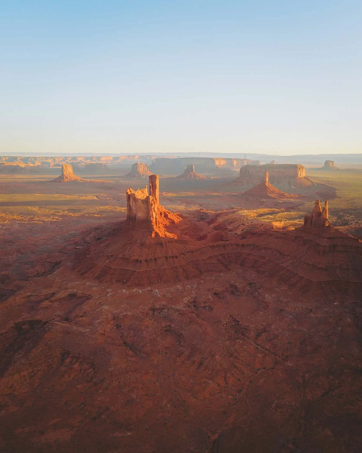 Panorama aérien drone Monument Valley Navajo Nation coucher de soleil. Formations rocheuses The Mittens et Merrick Butte désert rouge frontière Arizona Utah roadtrip ouest américain western John Ford Point.