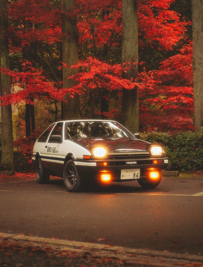 La légendaire Toyota AE86 Trueno posant sous les érables rouges (Momiji) en automne au Japon. Une photo iconique pour les fans d'automobile et de JDM.