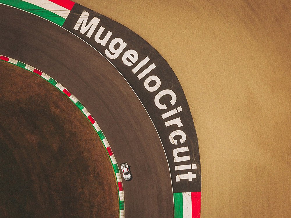 Vue aérienne verticale du lettrage "Mugello Circuit" en Italie avec une voiture de course en piste. Photographie sport automobile.