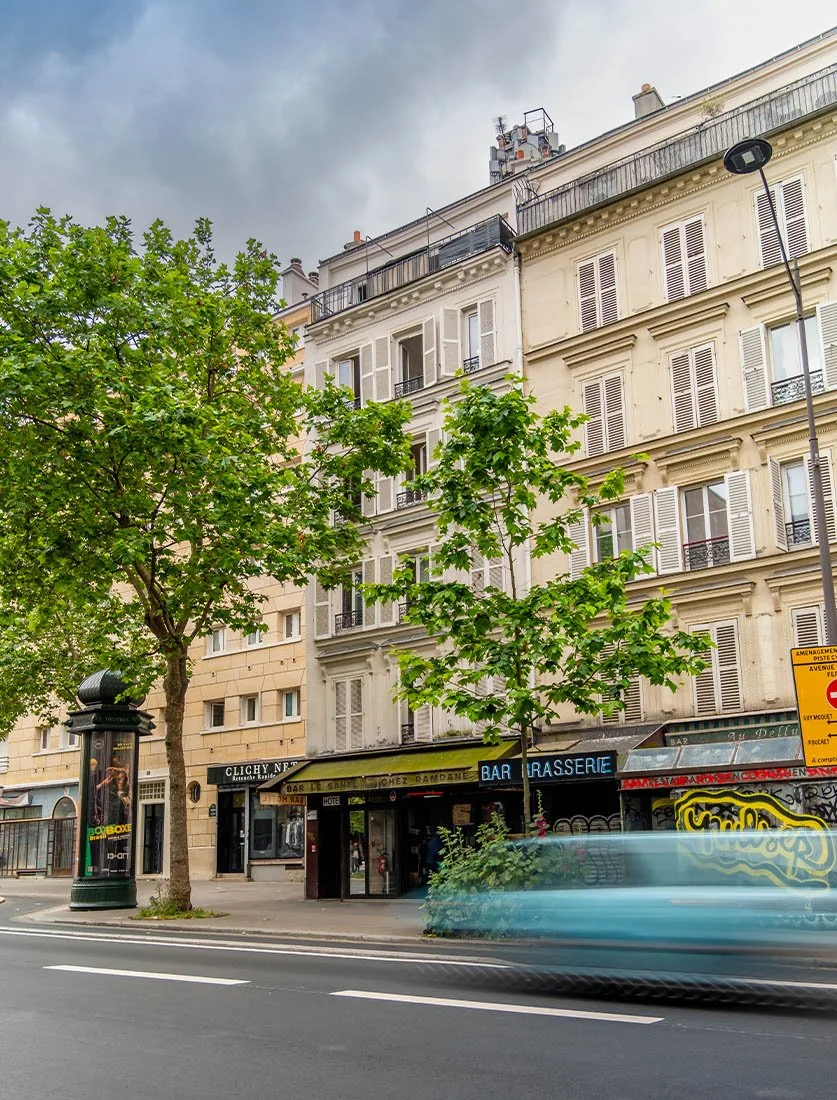 Photo urbaine dynamique à Paris montrant une façade typique et l'énergie de la ville (flou de mouvement). Réalisée par Dimitri Weber, photographe d'architecture capturant la vie autour des bâtiments.