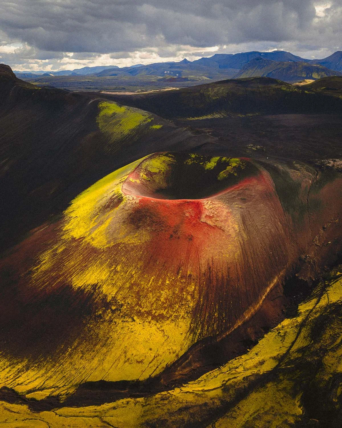 Les flancs rouge vif d'un volcan de scories le long de la piste F225, évoquant un paysage martien au cœur de l'Islande.