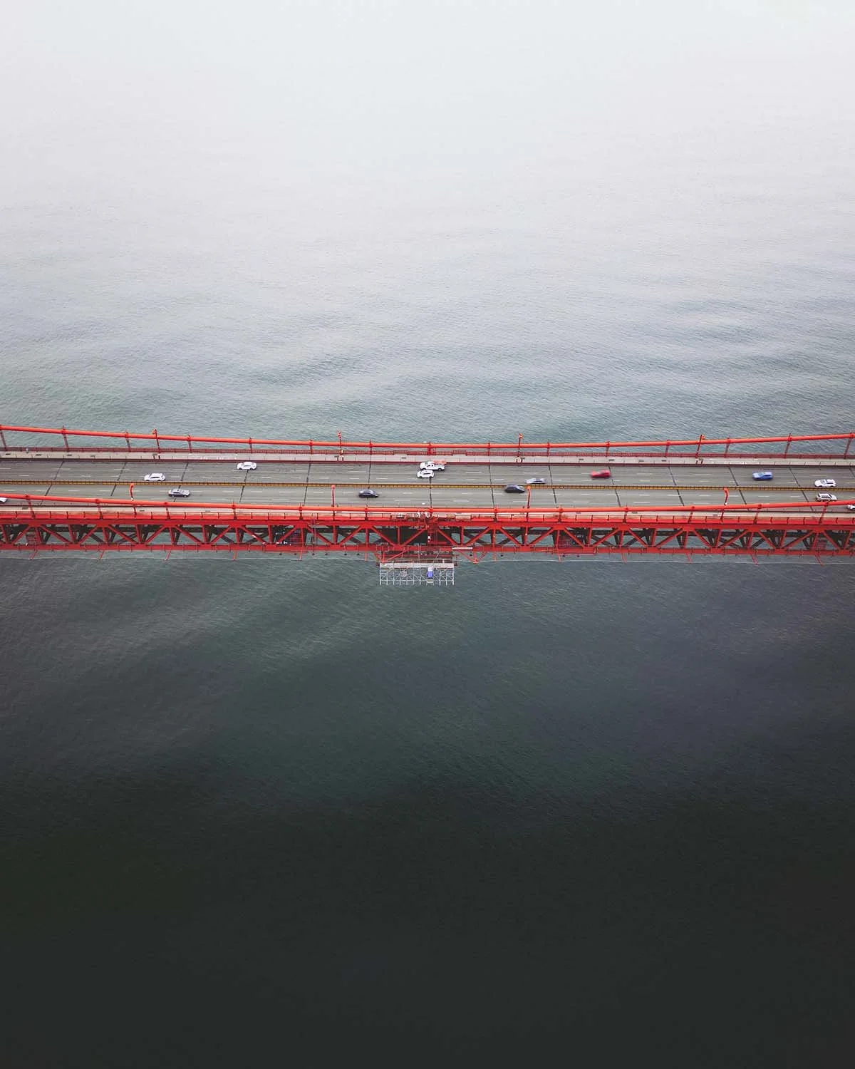 Vue aérienne drone verticale pont Golden Gate Bridge San Francisco rouge traffic voitures océan. Architecture génie civil structure métallique emblème Californie tourisme USA baie de San Francisco.