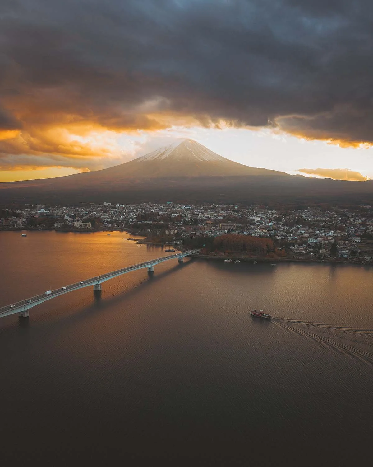 Paysage Mont Fuji vue du ciel drone lac Kawaguchiko pont Kawaguchiko Ohashi Bridge crépuscule golden hour. Panorama emblématique Japon Yamanashi tourisme nature volcan sacré nuages dramatiques.