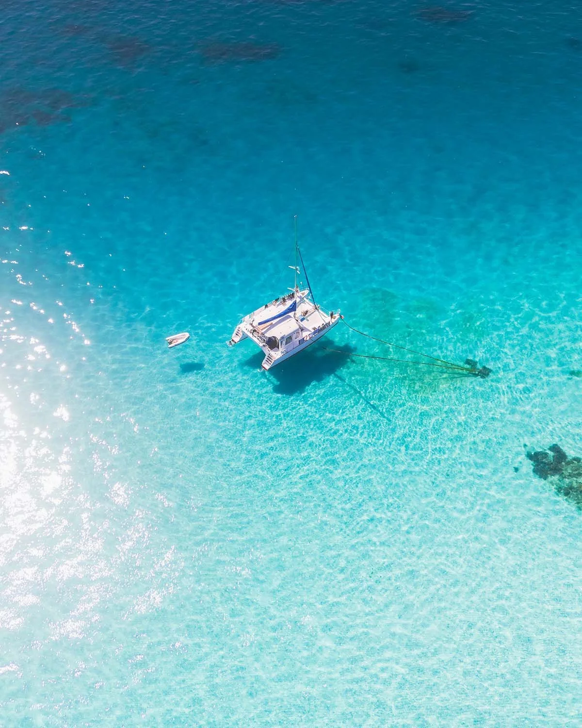 Catamaran au mouillage dans les eaux turquoise translucides de l'archipel des Whitsundays, au cœur de la Grande Barrière de Corail. Photographie de voyage lifestyle.