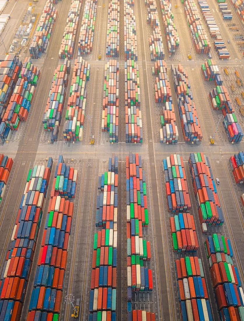 Vue d'ensemble spectaculaire d'un terminal portuaire, montrant l'alignement parfait des milliers de conteneurs. Photographie secteur logistique.