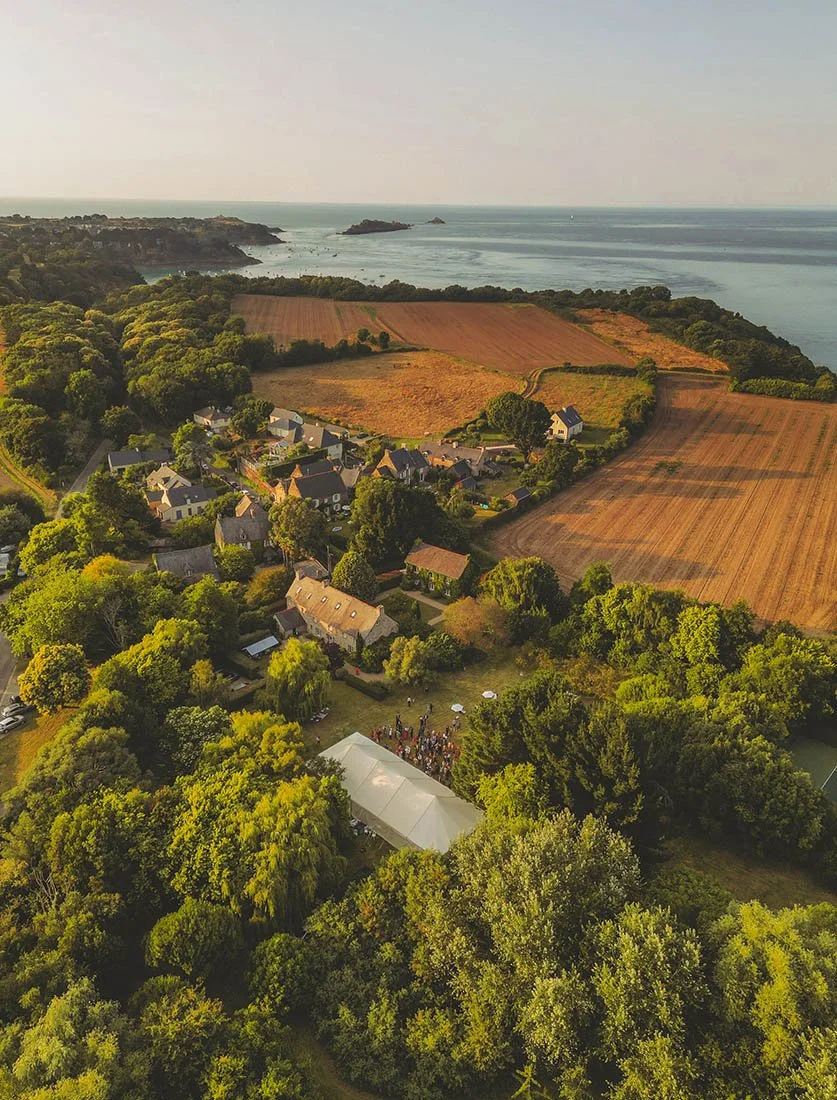 Vue aérienne sublime d'un domaine de mariage en bord de mer (type Bretagne) avec chapiteau de réception. Valorisation des lieux d'exception par drone.