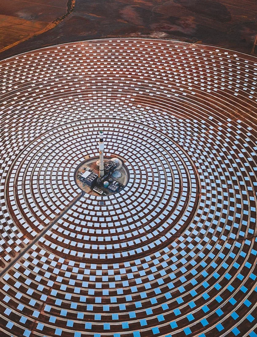 Vue panoramique large d'un champ de miroirs solaires dans le désert. Photographie d'infrastructures énergétiques.