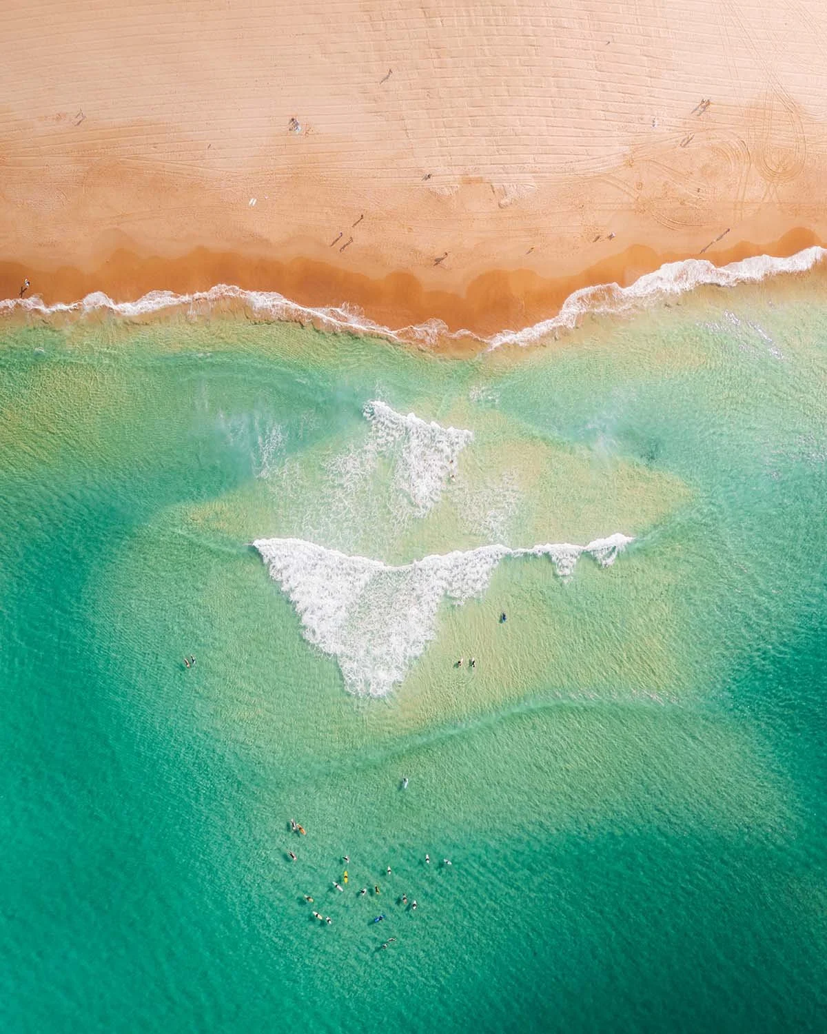 Texture marine vue du ciel : nageurs et surfeurs profitant des eaux cristallines et des bancs de sable d'une plage australienne typique (Gold Coast ou Sydney).