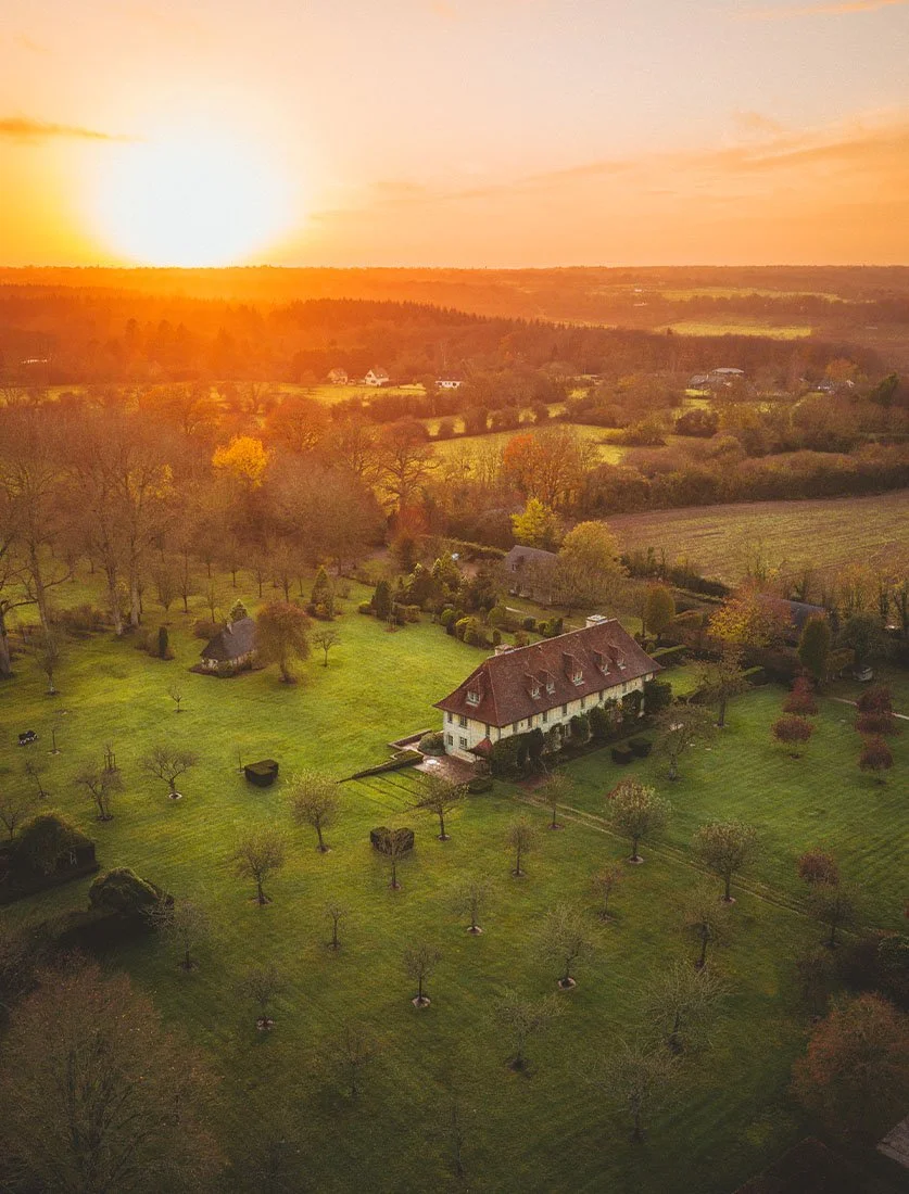 Photographie aérienne d'une propriété de caractère (Manoir) sublimée par la lumière dorée du coucher de soleil. Dimitri Weber, photographe immobilier de prestige, capture l'essence des biens d'exception.