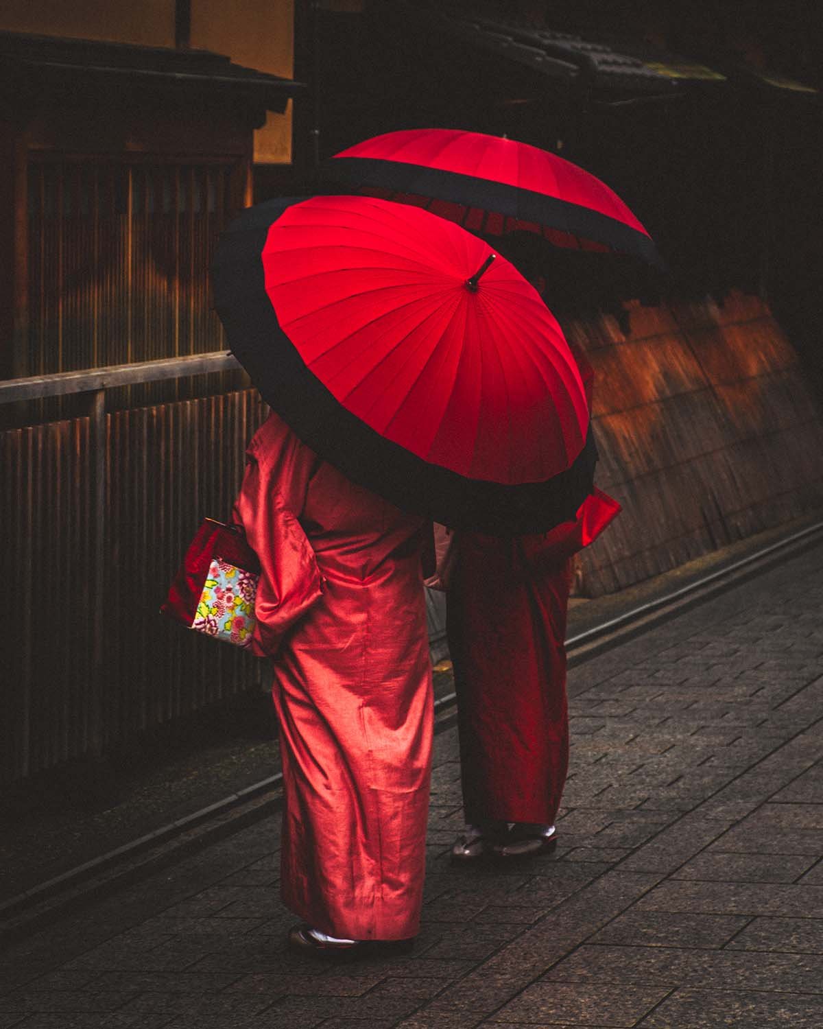 Élégance traditionnelle sous la pluie. Le contraste du rouge intense sur les pavés mouillés de Kyoto.