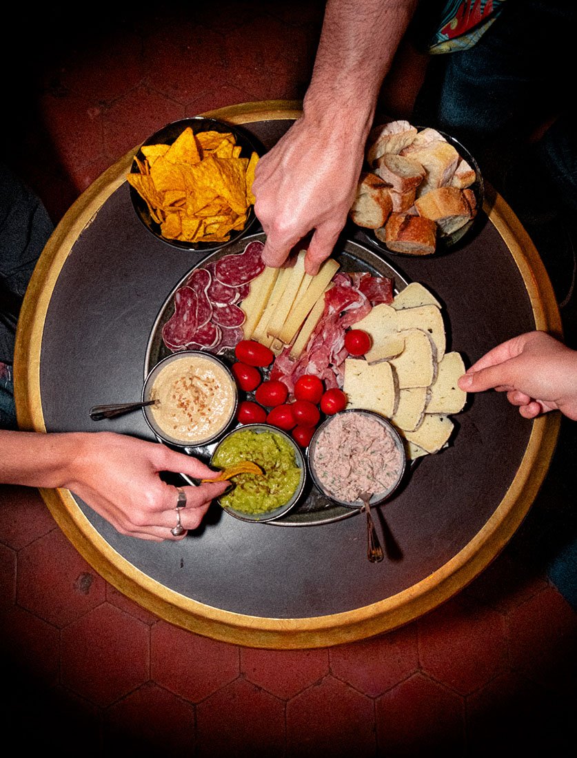 Vue de dessus (Flatlay) conviviale d'une planche apéritive partagée entre amis. Une image illustrant la convivialité et la gastronomie.