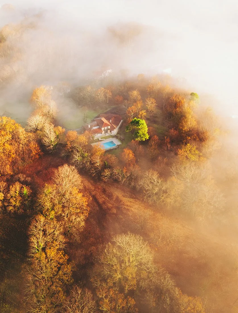 Photographie d'ambiance capturant une propriété isolée émergeant de la brume automnale. Un cliché illustrant l'approche artistique et narrative de Dimitri Weber, photographe architecture et paysage.
