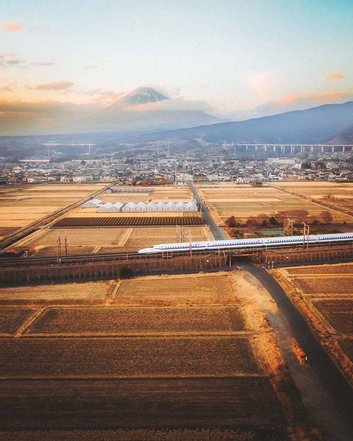 Le train à grande vitesse Shinkansen passant devant le Mont Fuji au coucher du soleil, traversant les rizières japonaises. Capture iconique du Japon par Dimitri Weber.
