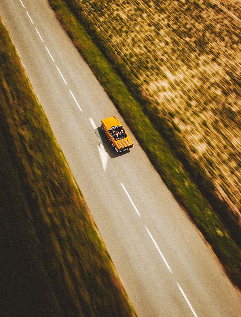 Shooting aérien avec un drone de la voiture des mariés qui partent du mariage par la route