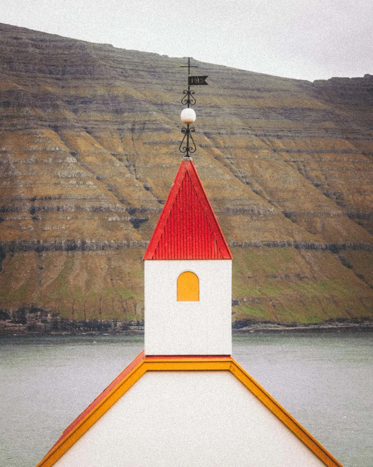 Petite église typique des Îles Féroé (Kollur) isolée au milieu des montagnes vertes et des fjords. Architecture religieuse nordique. 