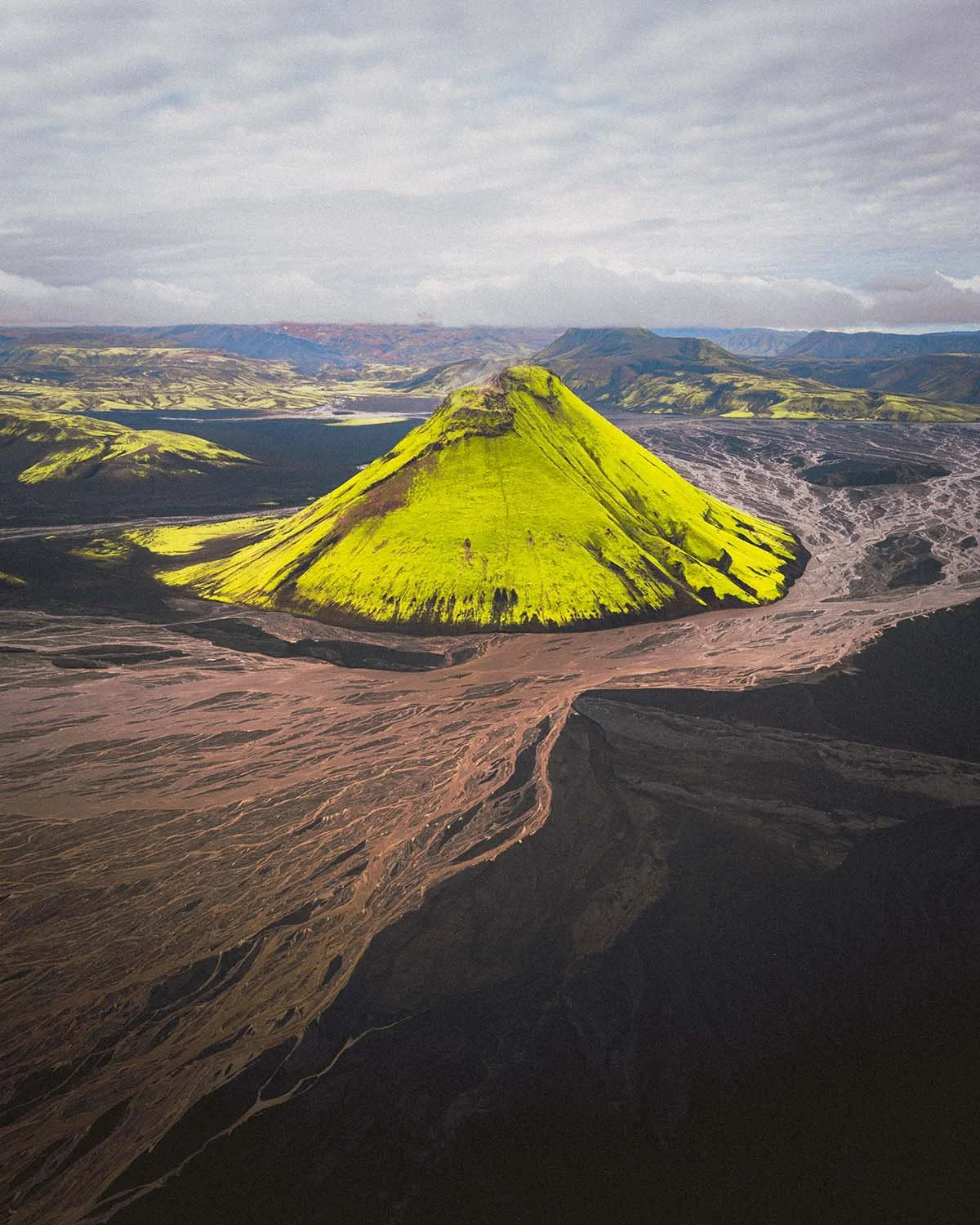 Le volcan Mælifell, cône parfait recouvert de mousse verte, isolé au milieu du désert de sable noir du Mælifellssandur. La photo drone ultime des Highlands par Dimitri Weber.