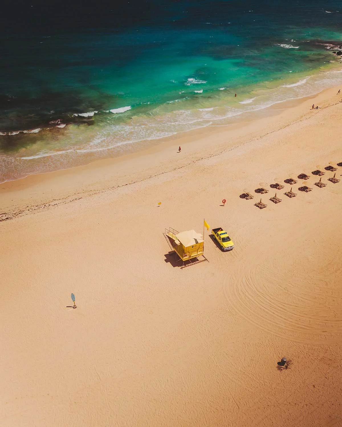 Minimalisme balnéaire : plage de sable doré, eau turquoise et poste de secours jaune vif sur les Grandes Playas de Corralejo à Fuerteventura.
