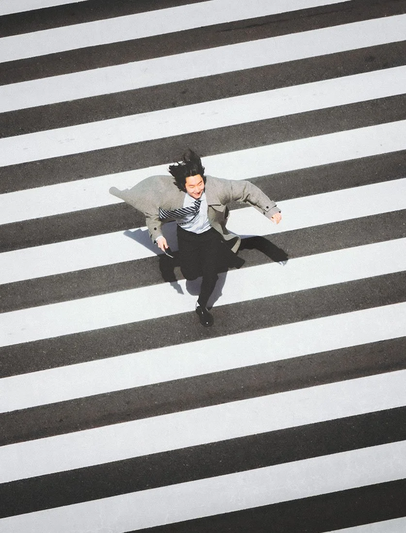 Le rythme effréné de Tokyo : un salaryman courant sur un passage piéton, capturé avec un angle en plongée graphique. Street photography au Japon.